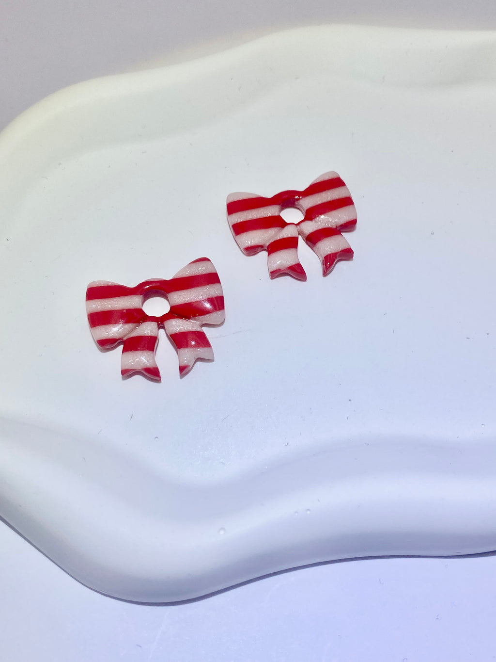 Paire de créoles boucles d'oreilles nœud rayé rouge et blanc montées sur des anneaux en acier inoxydable couleur or, création artisanale française.